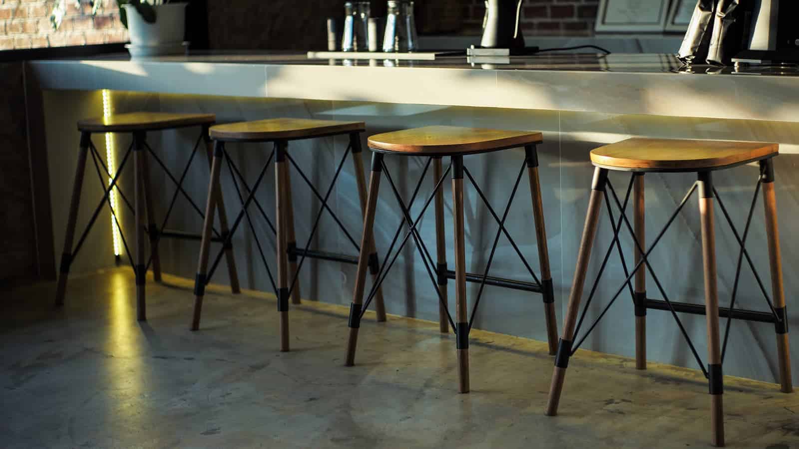 Set of modern wooden bar stools with metal legs at a counter.